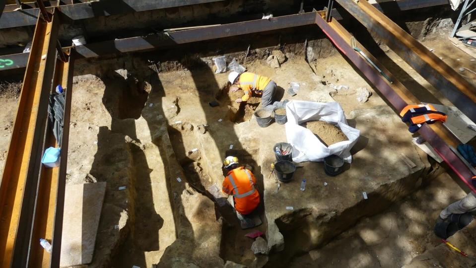 Two archaeologists wearing high visibility vests excavate the Saint-James necropolis in central Paris.