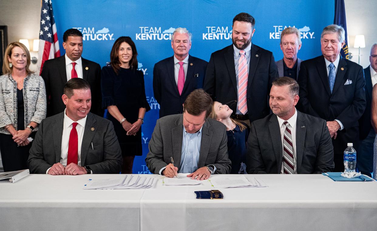 Surrounded by lawmakers and members of the Kentucky Horse Racing Commission, Kentucky Governor Andy Beshear, center, signs off on the regulations that will guide officials as they roll out sports wagering around the state. July 10, 2023