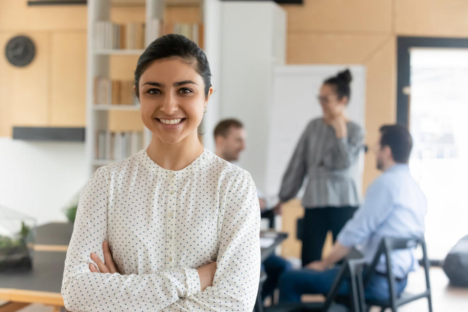 A woman stands with her arms crossed in a classroom