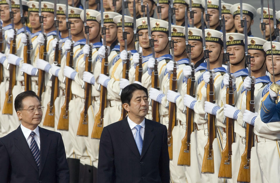 FILE - Chinese Premier Wen Jiabao, at left walks with Japanese Prime Minister Shinzo Abe as they inspect a guard of honor during the welcome ceremony held outside the Great Hall of the People in Beijing, China, Sunday, Oct. 8, 2006. Former Japanese Prime Minister Abe, a divisive arch-conservative and one of his nation's most powerful and influential figures, has died after being shot during a campaign speech Friday, July 8, 2022, in western Japan, hospital officials said. (AP Photo/Ng Han Guan, File)