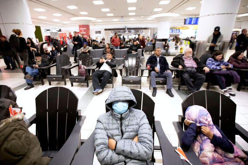 People wearing masks wait for arrivals at Pearson airport in Toronto