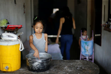 One of Yennifer Padron and Victor Cordova's daughters touches hot water in a pot in the house where they live at Petare slum in Caracas, Venezuela, August 21, 2017. REUTERS/Andres Martinez Casares/Files