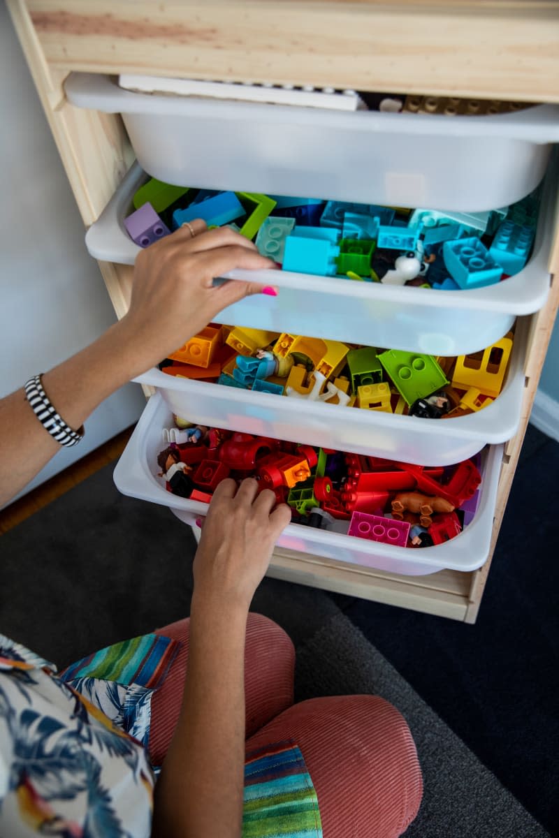 hands pulling open 3 white plastic storage trays filled with colorful legos