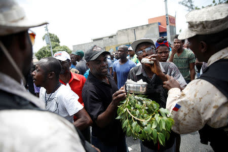 A demonstrator pretends to eat rocks in front of Haitian National Police officers during a protest in Port-au-Prince, Haiti, July 14, 2018. REUTERS/Andres Martinez Casares
