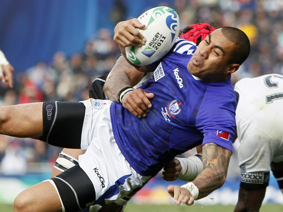 FILE - In this Sunday, Sept. 25, 2011 file photo, Samoa's Tusi Pisi is tackled by Fiji's Netani Talei during their Rugby World Cup game in Auckland, New Zealand. Samoa's best tournaments were before rugby turned openly professional, and the transition has been a double-edged sword for the tiny islands. At age 37, the flyhalf Tusi Pisi has been summoned for a third Rugby World Cup starting Friday Sept. 20, 2019. (AP Photo/Alastair Grant, File)