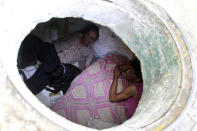 Miguel Restrepo (L), 62, and wife Maria Garcia are seen from their sewer home in Medellin December 4, 2012. The former drug addict has been living in an abandoned sewer with his wife and dog Blackie for 22 years. Their home, which is fitted with a kitchen, a fan, tv, a chair and a bed, is a 6 square meter wide and 1.4 meters high tunnel that leaks when it rains, and requires a manhole cover. REUTERS/Albeiro Lopera (COLOMBIA - Tags: SOCIETY POVERTY) - RTR3B7PH