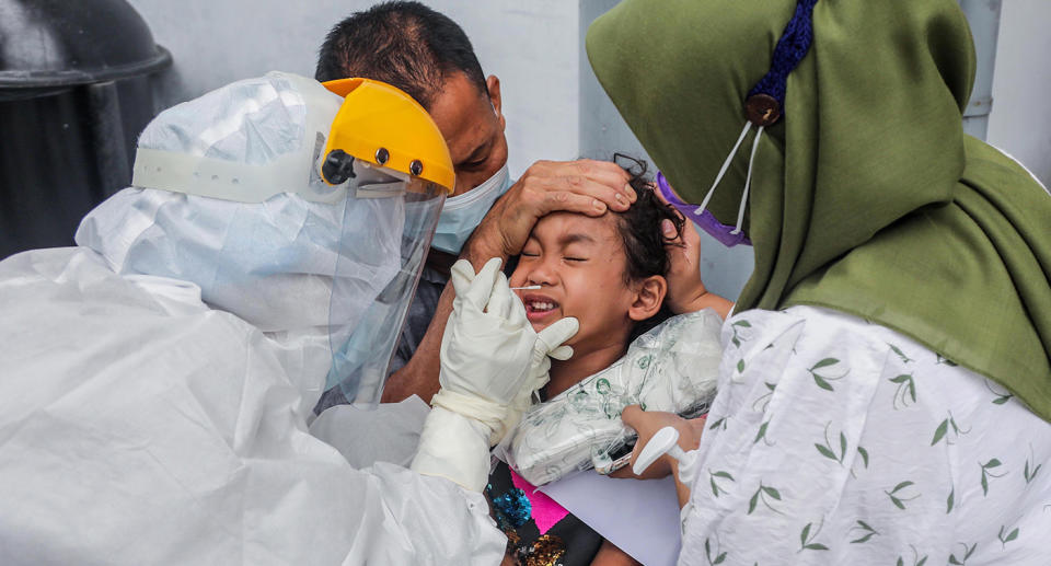 A healthcare worker in a hazmat suit collects specimen samples from a girl during a COVID-19 swab test in Medan, North Sumatra, Indonesia, 26 April 2021. Indonesia has banned foreign travelers from India over the Covid-19 scare, official said. Indonesia has recorded more than 1,600,000 coronavirus disease (COVID-19) cases since the beginning of the pandemic.  EPA/DEDI SINUHAJI