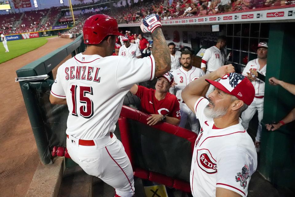 Cincinnati Reds center fielder Nick Senzel (15) is congratulated in the dugout by Cincinnati Reds hitting coach Alan Zinter (59) after hitting a solo home run during the seventh inning of a baseball game, Monday, July 4, 2022, at Great American Ball Park in Cincinnati.