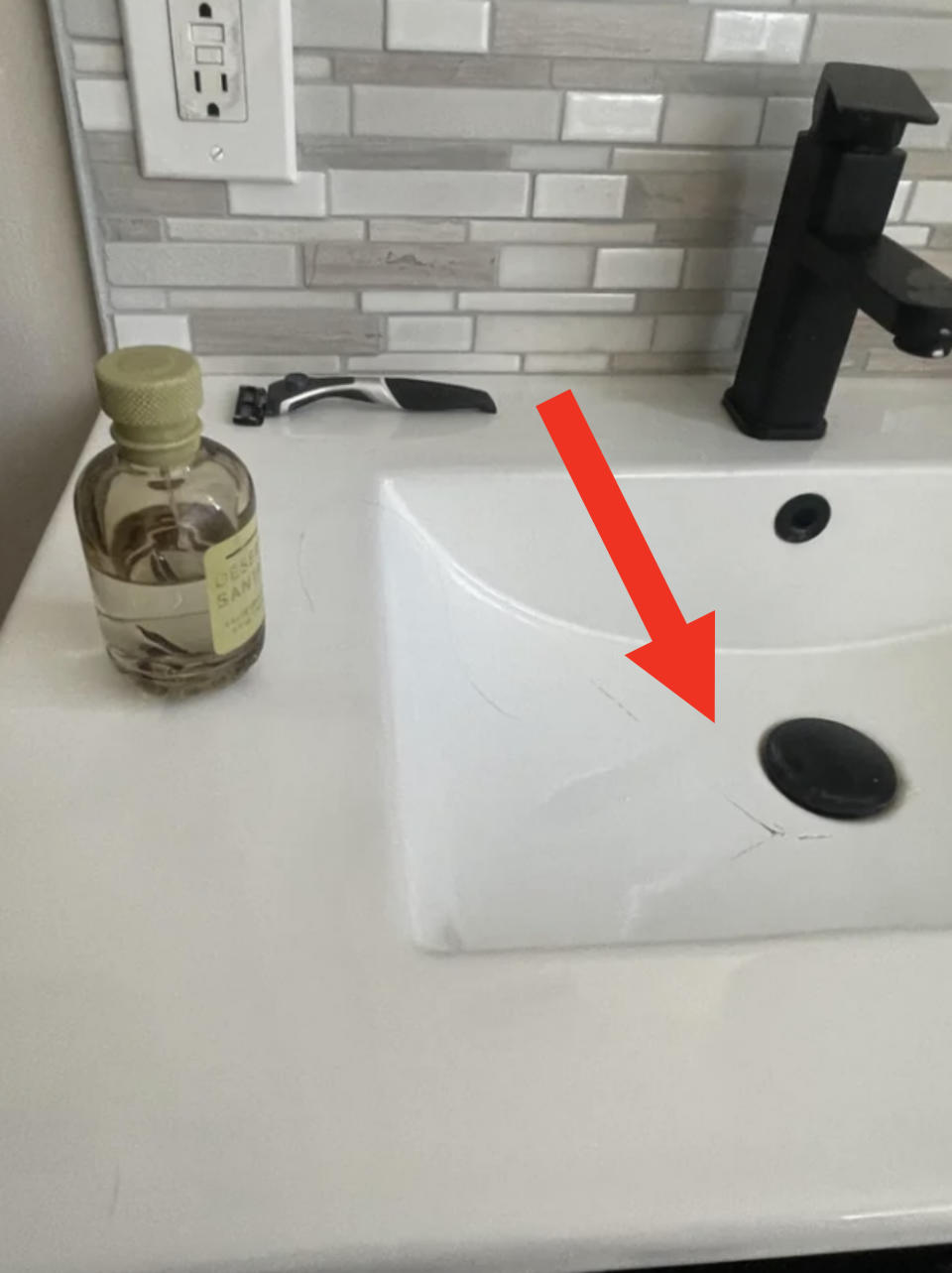 Bathroom sink with a bottle of Dr Teal's body oil and a black faucet