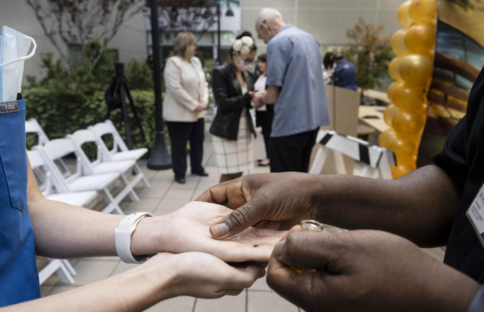 Chaplain Bill O'Brien, furthest, and Fr. Patrick Okonkwo perform a Blessing of the Hands at Providence St. Joseph Hospital in Orange, Calif., on Wednesday, May 11, 2022. The ceremony, in which nurses hands are anointed with oil, is intended to show the importance of physical touch in healthcare. (Paul Bersebach/The Orange County Register via AP)