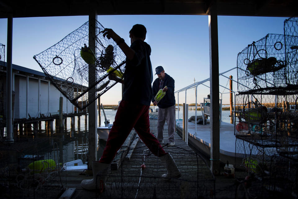 Image: Benjamin Eskridge, left, carries a crab trap while helping his grandfather Allen Crocket prepare for the next day of crabbing in Tangier, Va., on May 15, 2017. (Jim Watson / AFP via Getty Images file)