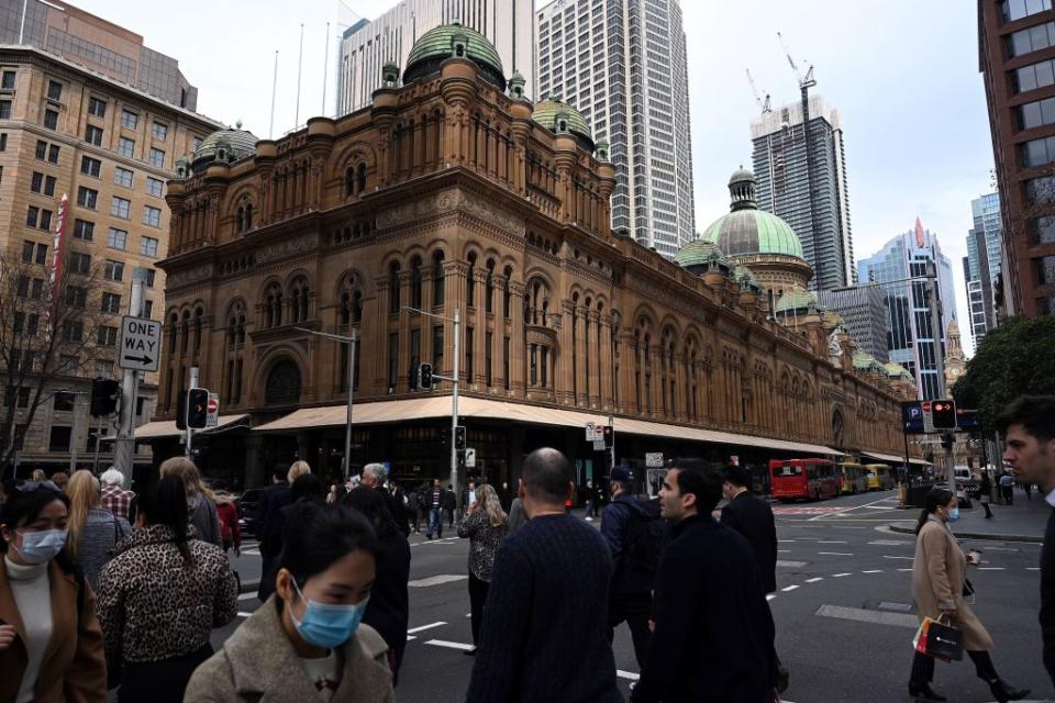 Pedestrians, some wearing face masks, walk through Sydney's central business district on August 12, 2020. (Photo by SAEED KHAN/AFP via Getty Images)