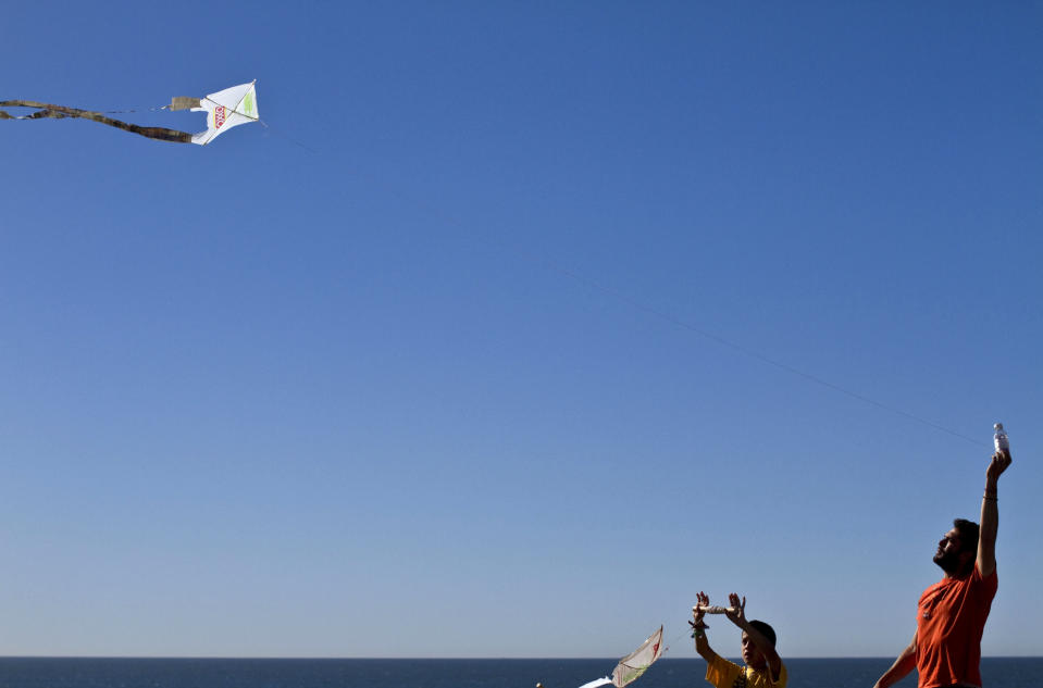 FILE - Dan Watman and a child fly kites made from discarded plastic bags and newspapers, near the US-Mexico border fence in Tijuana, Mexico, Nov. 13, 2010. Watman, of Friends of Friendship Park which advocates for cross-border park access, said the section of the Berlin Wall displayed near the border wall in Tijuana, that separates the United States from Mexico, is only a token gesture. “The park on the Mexican side has become sort of a one-sided party,” he said. (AP Photo/Guillermo Arias, File)