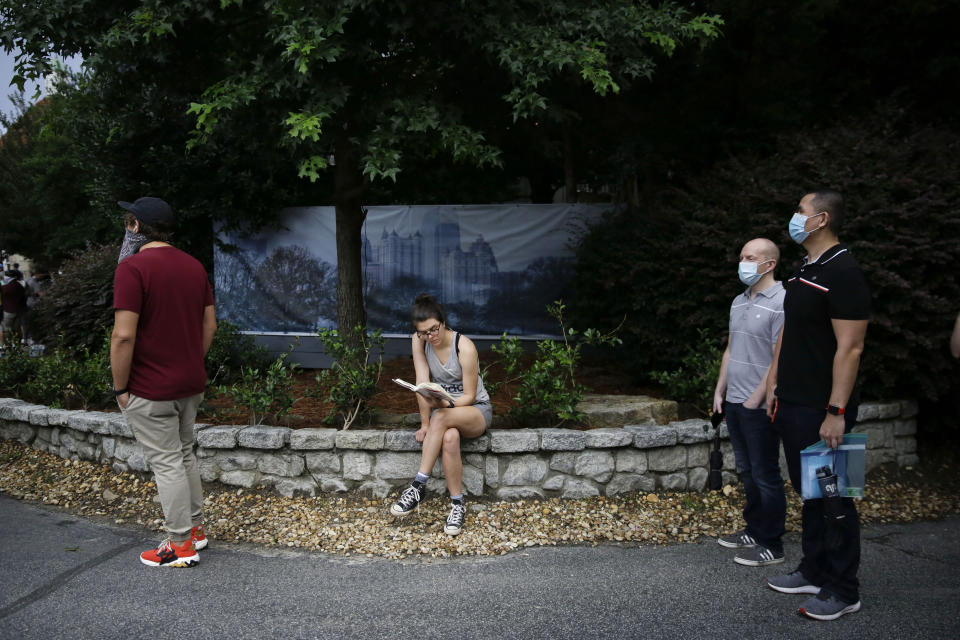 A person reads a book as they wait in line to vote in the Georgia's primary election at Park Tavern on Tuesday, June 9, 2020, in Atlanta. (AP Photo/Brynn Anderson)