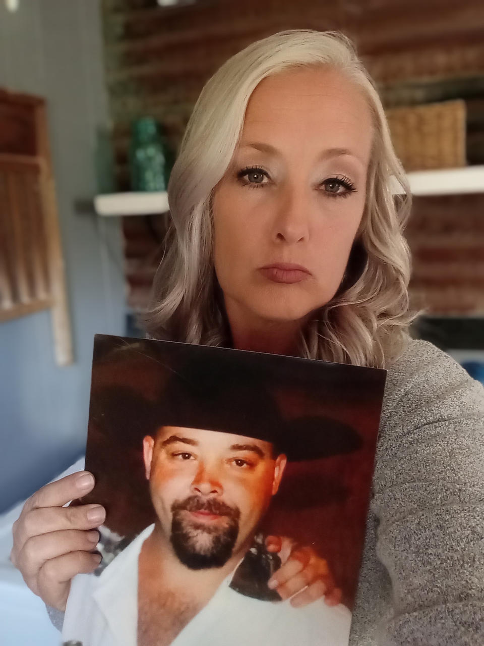 Jenifer Jones holds a photo of her deceased brother, John Wayne Dodge, on Wednesday, Nov. 2, 2023, at her home in San Jacinto County, Texas. Jones, 47, said she reached out to the FBI about what she feels was San Jacinto County Sheriff Greg Capers' office's botched investigation of her bother's fatal shooting and said agents questioned her for hours, asking about events well beyond her brother's case and collecting records accusing the sheriff and his staff of wide-ranging misconduct. (Jenifer Jones via AP)