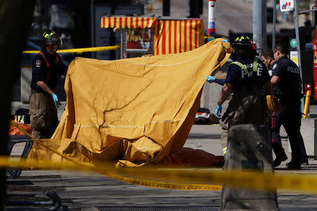 Emergency officials cover a body with a tarp at the scene of an incident where a van struck multiple people on Yonge Street in Toronto, Ontario, Canada, April 23, 2018. REUTERS/Carlo Allegri