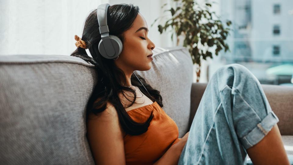 Shot of a young woman using headphones while relaxing on the sofa at home