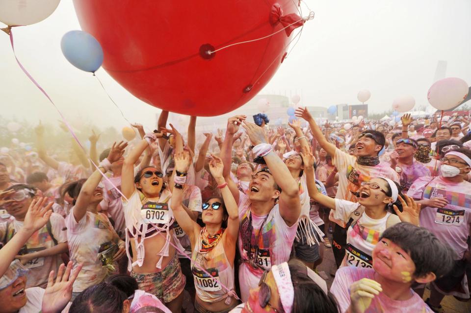 Participants covered with colour powder play with a giant balloon during a five-kilometre colour run event in Beijing