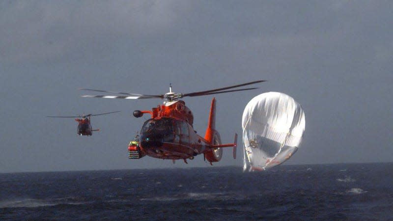 A photo of a helicopter flying away from the wreckage of a balloon crash. 