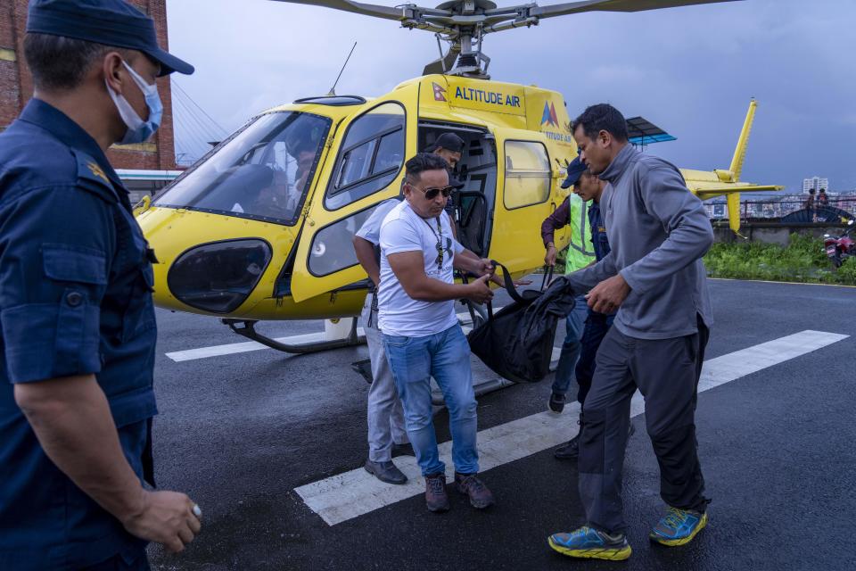 People carry the body of a victim of a tourist helicopter crash in Kathmandu, Nepal, July 11, 2023, off of another helicopter that came to aid in the recovery operation. / Credit: Niranjan Shrestha/AP