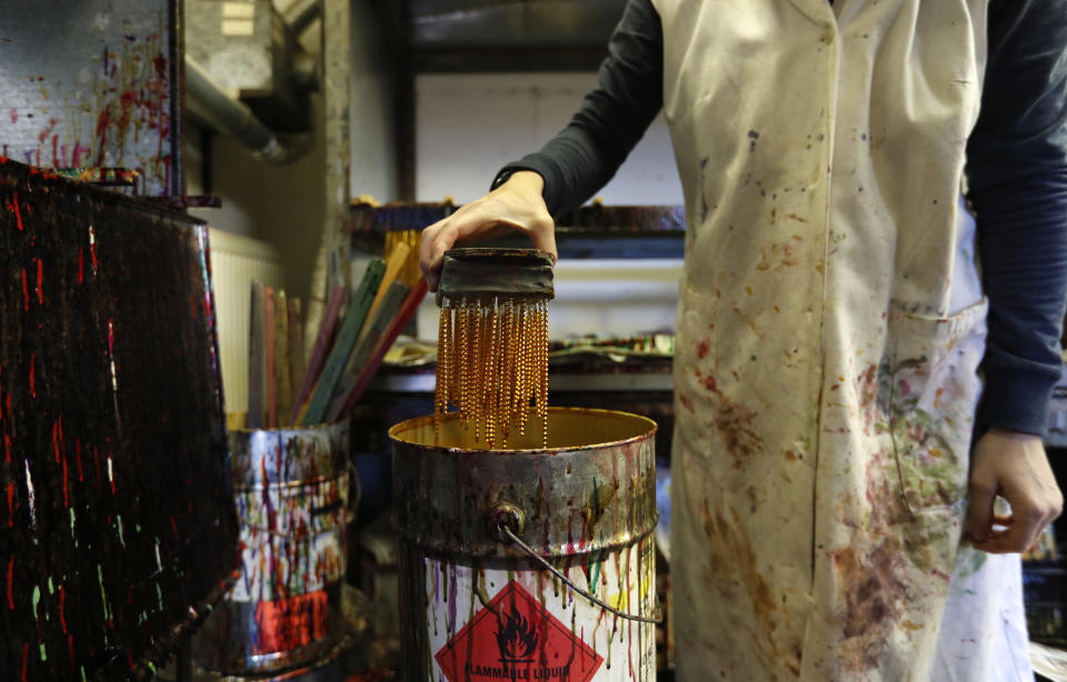 In this picture taken on Wednesday, Nov. 28, 2018, a worker colours small blown glass beads in the village of Ponikla, Czech Republic. The small family business in a mountainous village in northern Czech Republic is the last place in the world where traditional Christmas decorations are made from glass beads blown and painted by hand. (AP Photo/Petr David Josek)