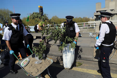 Police officers remove trees and other items during the Extinction Rebellion protest on Waterloo Bridge in London, Britain April 20, 2019. REUTERS/Simon Dawson