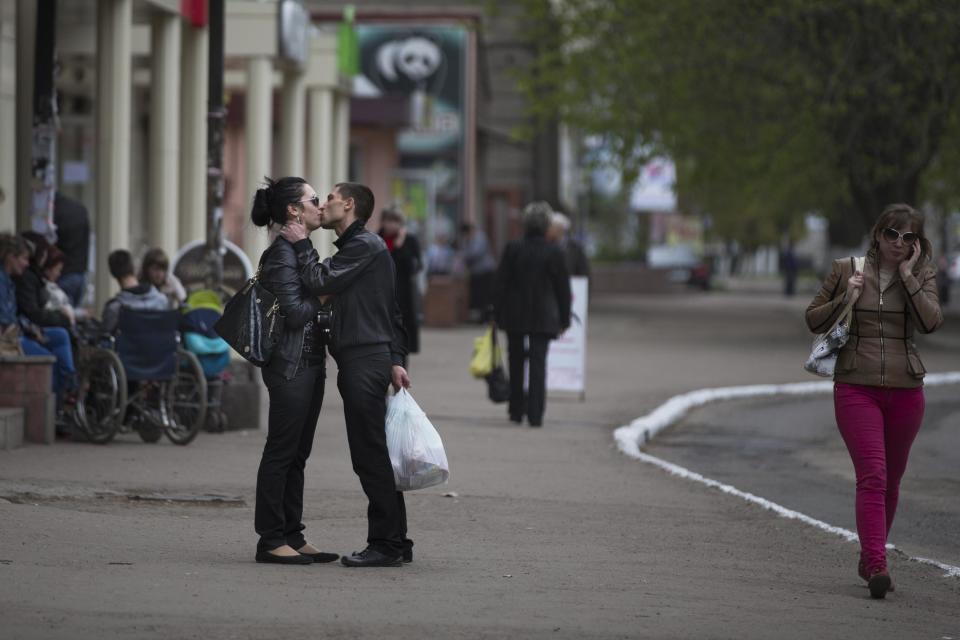 A young couple shares a tender moment in a street leading towards the barricade in Slovyansk, Ukraine, Saturday, April 19, 2014. Pro-Russian insurgents defiantly refused Friday to surrender their weapons or give up government buildings in eastern Ukraine, despite a diplomatic accord reached in Geneva and overtures from the government in Kiev.(AP Photo/Alexander Zemlianichenko)