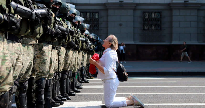 一名白俄羅斯的婦女，跪在當地鎮暴警察的面前阻攔警察動線。（圖／達志／美聯社）