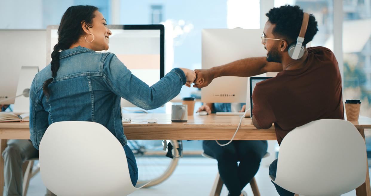 Rearview shot of two young designers giving each other a fist bump in an office