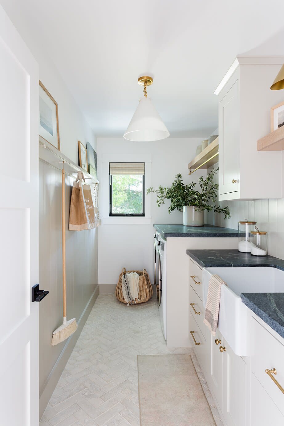 laundry room with off-white cabinets, dark stone counters, and brass hardware
