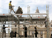 Construction workers set up scaffoldings in front of St. Peter's Basilica at the Vatican, Tuesday, April 22, 2014. The scaffoldings will be used by international media covering the canonization ceremony of two late popes; John Paul II and John XXIII, that will be held in St. Peter's Square on Sunday April 27, 2014. (AP Photo/Domenico Stinellis)