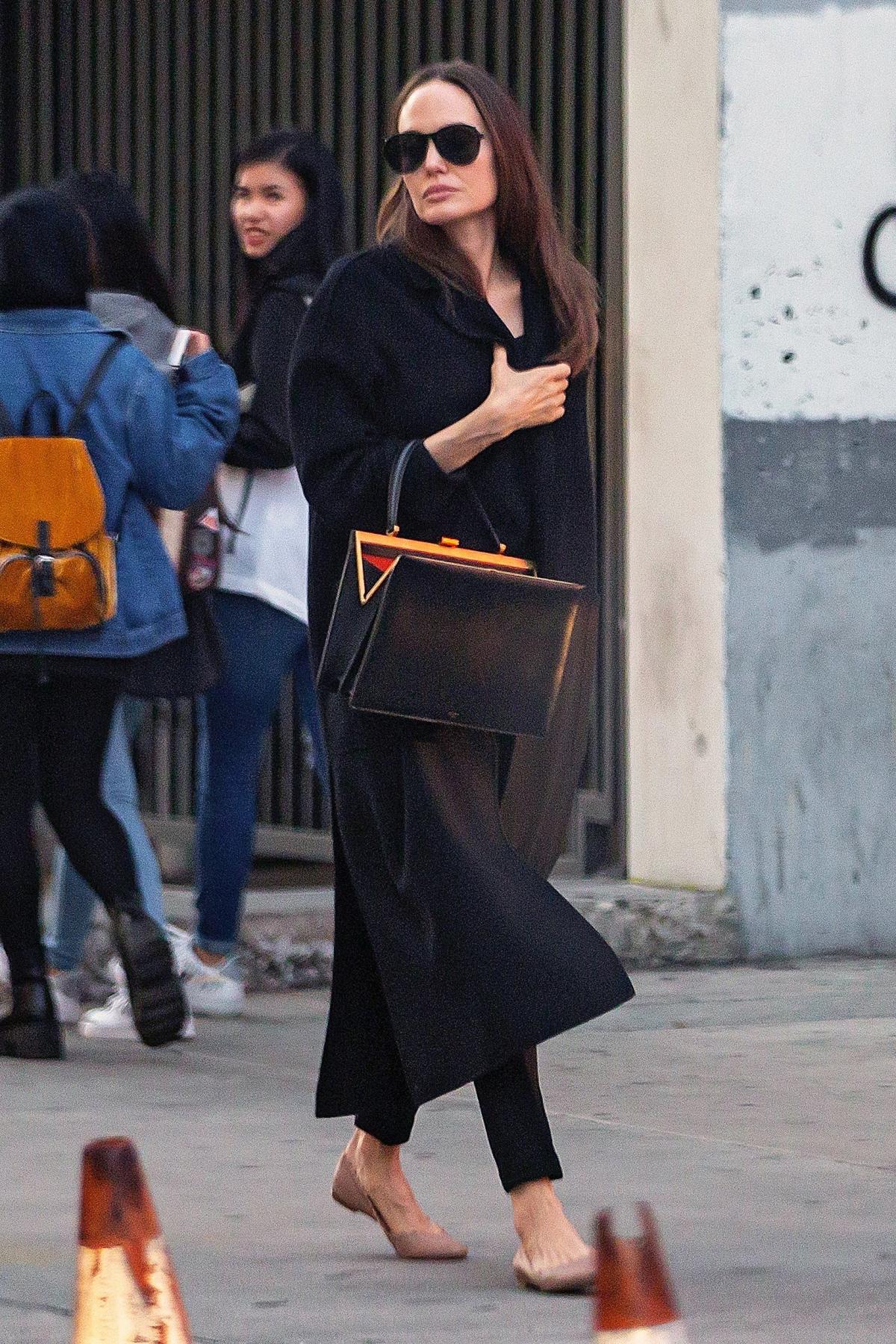 Who made Angelina Jolie's black handbag, brown flat slide sandals