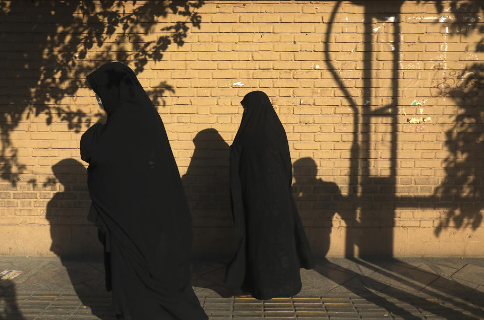 Women wearing protective face masks to help prevent the spread of the coronavirus walk on a sidewalk in southern Tehran, Iran, Tuesday, July 20, 2021. Iran on Tuesday broke another record in the country's daily new coronavirus cases, even as Tehran and its surroundings went into lockdown, a week-long measure imposed amid another surge in the pandemic. (AP Photo/Vahid Salemi)