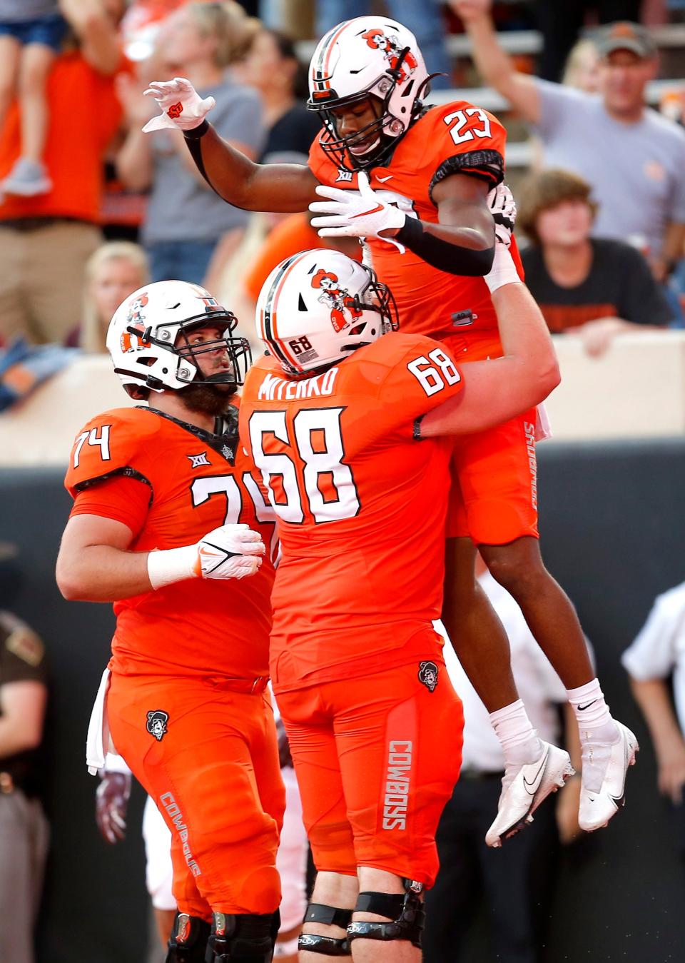 OSU's Jaden Nixon (23) celebrates a touchdown with Taylor Miterko (68) and Preston Wilson (74) in the second quarter of a 58-44 win.