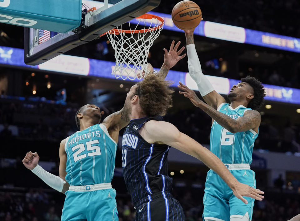 Charlotte Hornets forwards P.J. Washington, left, and Jalen McDaniels, right rebound over Orlando Magic center Robin Lopez, center, during the first half of an NBA basketball game on Thursday, April 7, 2022, in Charlotte, N.C. (AP Photo/Rusty Jones)