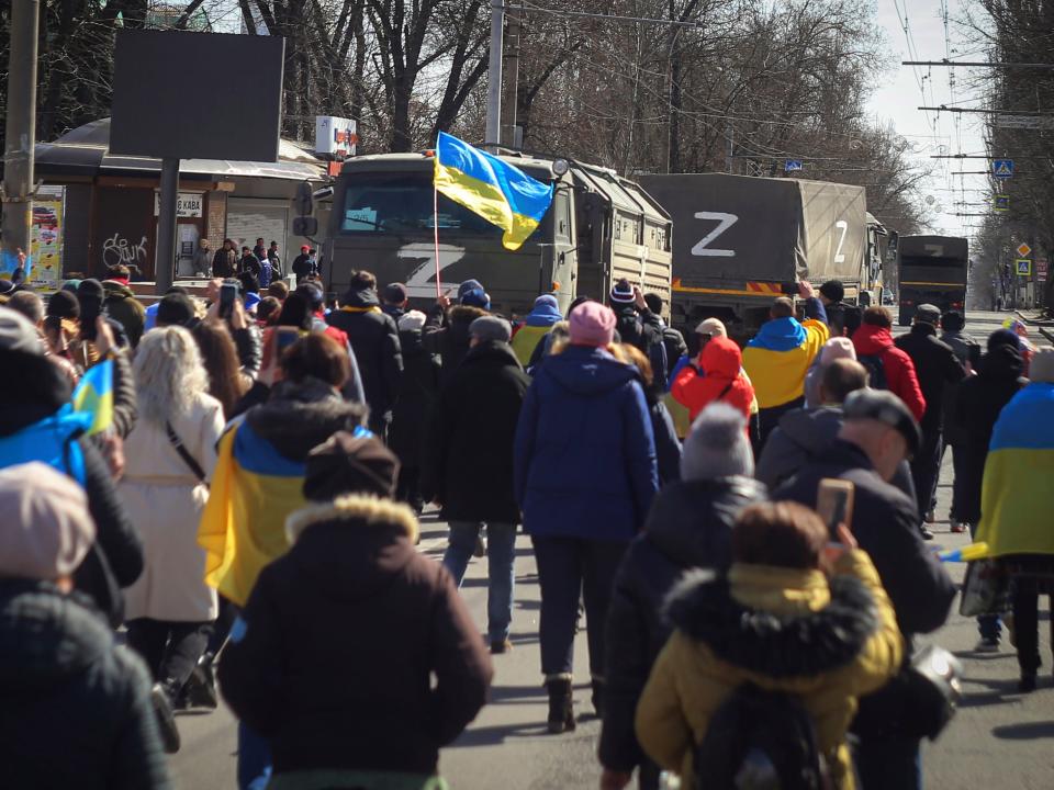 Ukrainian protesters walk toward Russian army trucks.