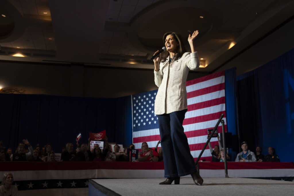 A woman in a suit standing in front of an American flag