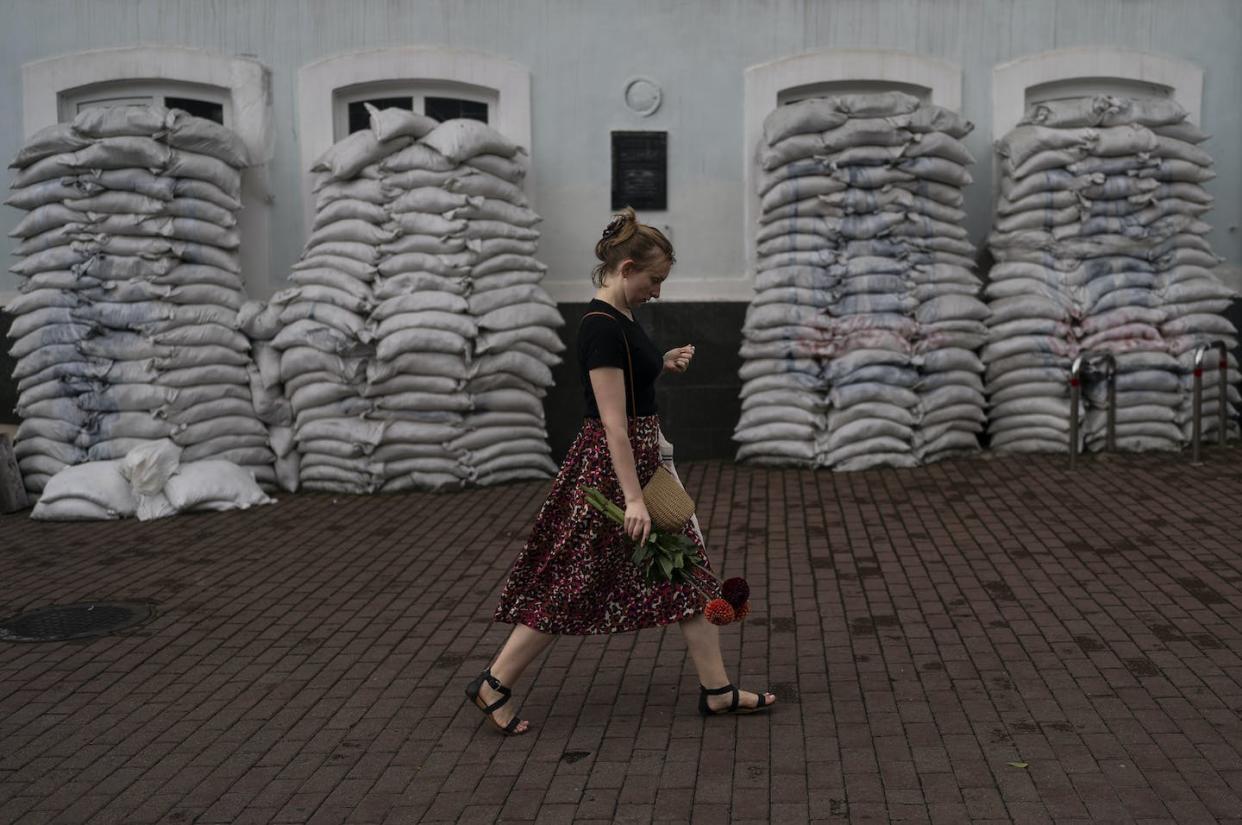 A woman with flowers walks past a building fortified with sandbags in the Podil neighborhood of Kyiv, Ukraine. <a href="https://newsroom.ap.org/detail/APTOPIX%20Russia%20Ukraine%20War%20Daily%20Life/36cd7048eb8347298d1f560a490b4bd7?Query=ukraine%20daily%20life&mediaType=photo&sortBy=arrivaldatetime:desc&dateRange=Anytime&totalCount=988&currentItemNo=125" rel="nofollow noopener" target="_blank" data-ylk="slk:AP Photo/Jae C. Hong;elm:context_link;itc:0;sec:content-canvas" class="link ">AP Photo/Jae C. Hong</a>