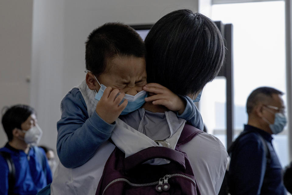 A child cries as he waits in line to board a plane for Beijing at the airport in Hong Kong on Feb. 9, 2020. (AP Photo/Ng Han Guan)