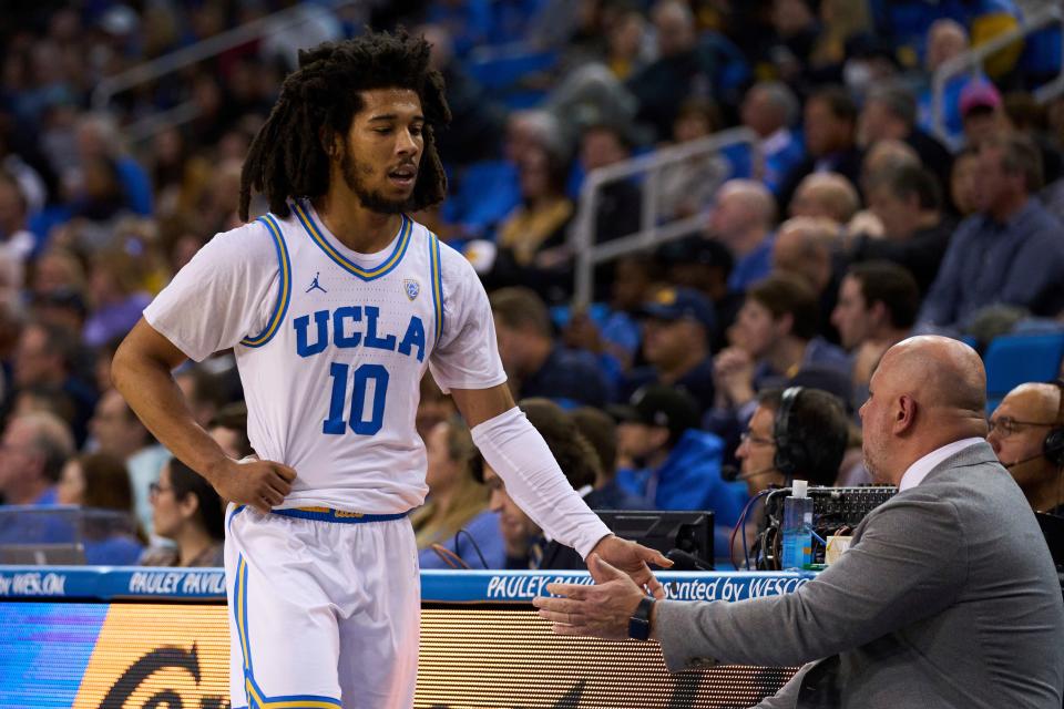 UCLA guard Tyger Campbell (10) is greeted by assistant coach Darren Savino during the first half of the team's NCAA college basketball game against California on Saturday, Feb. 18, 2023, in Los Angeles. (AP Photo/Allison Dinner)