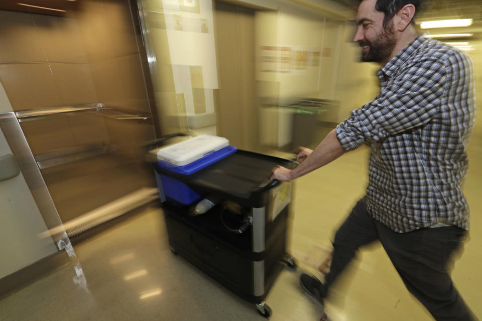 In this Jan. 14, 2020 photo, Chris Hill rushes a cooler containing a piece of live brain tissue into an elevator at Harborview Medical Center in Seattle after it was donated by Genette Hofmann as she underwent brain surgery for epileptic seizures that had disrupted her life for decades. As part of the surgery, Hofmann agreed to donate a small bit of her healthy brain tissue to researchers at the Allen Institute, who were eager to study brain cells while they were still alive, joining a long line of epilepsy patients who've helped scientists reveal basic secrets of the brain. (AP Photo/Ted S. Warren)