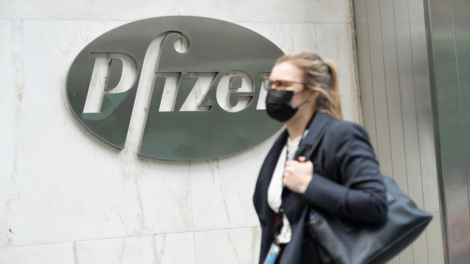 A woman wearing a face mask walks past a Pfizer logo at their Headquarters. (John Nacion/SOPA Images/LightRocket via Getty Images)