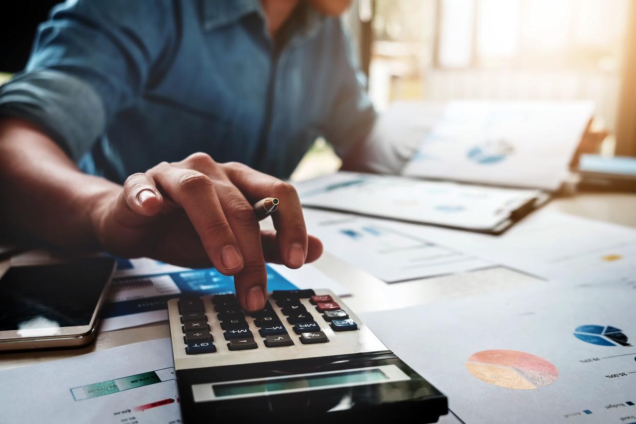 business man using calculator with computer laptop, budget and loan paper in office