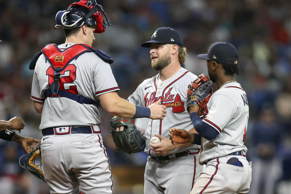 Atlanta Braves relief pitcher A.J. Minter, center, is attended to by catcher Sean Murphy (12) and Ozzie Albies, right. before being removed during the eighth inning of a baseball game against the Tampa Bay Rays, Saturday, July 8, 2023, in St. Petersburg, Fla. (AP Photo/Mike Carlson)