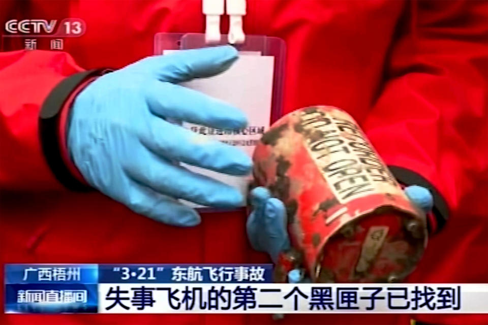 In this image taken from video footage run by China's CCTV, a search and rescue worker holds the second orange-colored "black box" recorder which recovered at the China Eastern flight crash site in Tengxian County on Sunday, March 27, 2022, in southern China's Guangxi Zhuang Autonomous Region. The second "black box" has been recovered from the crash of a China Eastern Boeing 737-800 that killed all 132 people on board last week, Chinese state media said Sunday. (CCTV via AP Video)