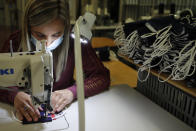 In this Friday, June 12, 2020 photo, an employee sews face protective masks in Chanteclair Hosiery, a French knitwear clothing manufacturer, in Saint Pouange, east of Paris. The French praised the altruism of luxury goods companies such as LVMH, Kering and Chanel for diverting their production facilities to make millions of face masks for the public during the peak of their country's coronavirus outbreak. Now, the companies that helped France avoid a dangerous shortage say they need help unloading a surplus of 20 million washable masks. (AP Photo/Francois Mori)