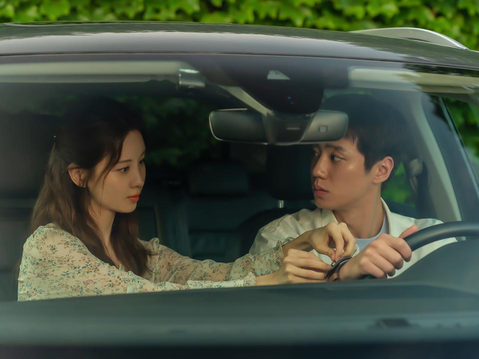 main characters of love and leashes sitting in a car