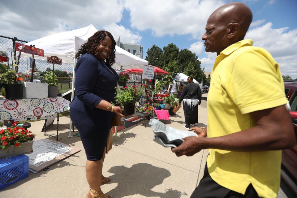 Reggie Garner of Buffalo gives Tracy Bates a free plant after earlier trying to sell her one at the outdoor market, Kuleta Pamoja (Swahili for come together), on Jefferson Avenue in Buffalo, NY, Saturday, July 30, 2022. The outdoor market is one of the programs at the Johnnie B. Wiley Amateur Athletic Sports Pavilion. that runs throughout the summer. Garner's house on Rodney Street is filled with plants that he grew and is also on the East Side Garden Walk.