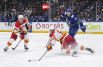 Calgary Flames' Ilya Solovyov falls while vying for the puck against Vancouver Canucks' Teddy Blueger (53) as Flames' Brayden Pachal (94) watches during the second period of an NHL hockey game Tuesday, April 16, 2024, in Vancouver, British Columbia. (Darryl Dyck/The Canadian Press via AP)