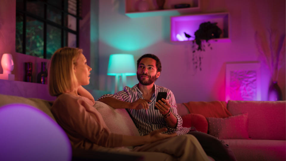 Philips Hue smart lights illuminate a room as two people chat on a couch. - Credit: Christian de Looper for BGR